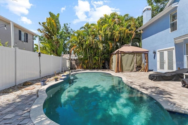 view of swimming pool with a fenced in pool, a fenced backyard, a gazebo, french doors, and a patio area
