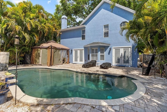 pool with french doors, a gazebo, fence, and a patio area