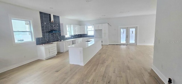 745 31st Ave N, Saint Petersburg, FL 33704 - kitchen featuring white cabinetry, light wood-style flooring, tasteful backsplash, a kitchen island, and light countertops