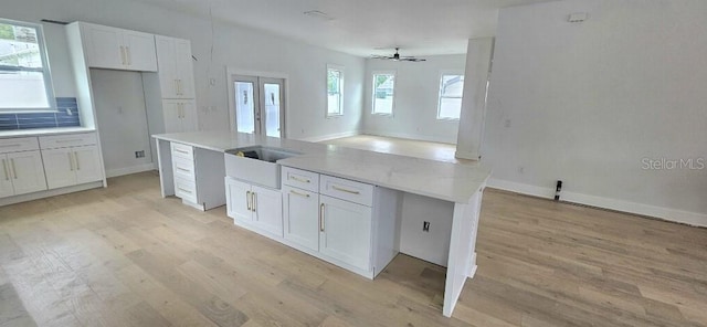 745 31st Ave N, Saint Petersburg, FL 33704 - kitchen with light wood finished floors, white cabinets, a ceiling fan, a kitchen island, and french doors
