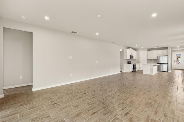17800 Solstice Ave, Venice, FL 34293 - unfurnished living room featuring a sink, baseboards, light wood-type flooring, and recessed lighting