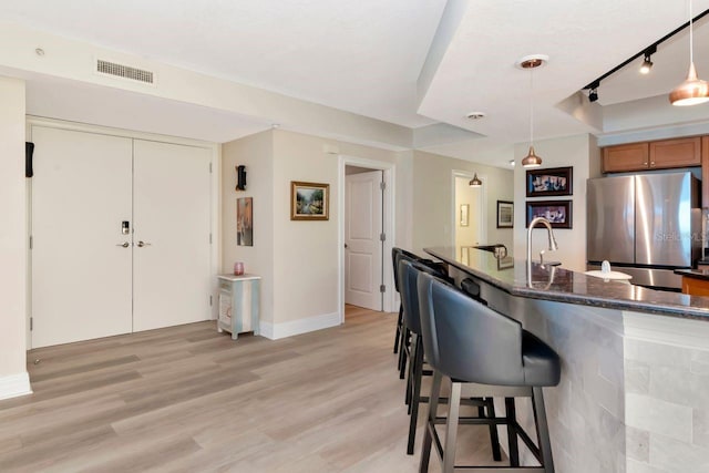 1350 Gulf Blvd Unit 301, Clearwater Beach, FL 33767 - kitchen with light wood-style floors, a kitchen bar, rail lighting, visible vents, and freestanding refrigerator