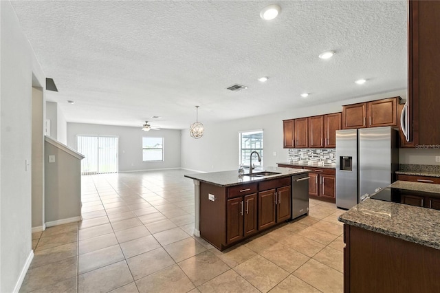 14050 Arbor Pines Dr, Riverview, FL 33579 - kitchen with stainless steel appliances, healthy amount of natural light, an island with sink, decorative backsplash, and a textured ceiling