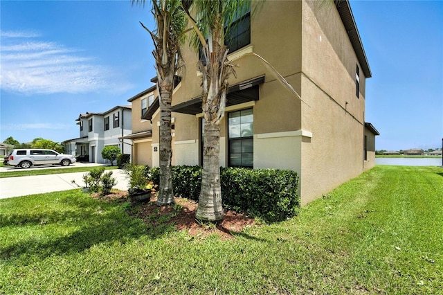 14050 Arbor Pines Dr, Riverview, FL 33579 - view of side of home featuring stucco siding, concrete driveway, a lawn, a water view, and a garage