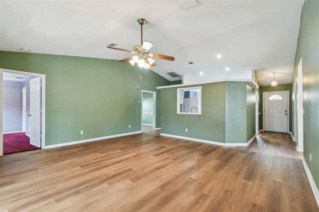 interior space featuring a ceiling fan, visible vents, vaulted ceiling, baseboards, and light wood-style flooring