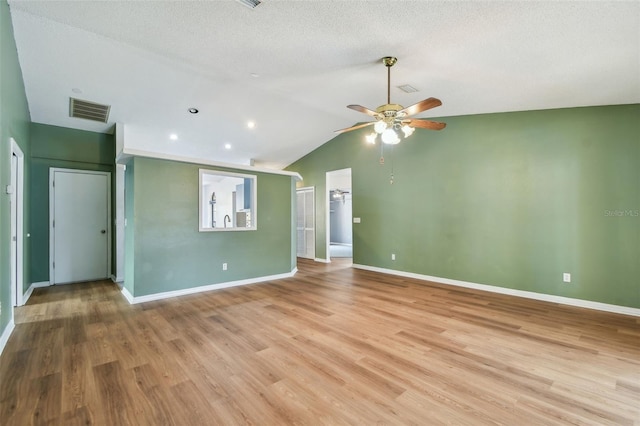unfurnished room featuring vaulted ceiling, light wood-style floors, visible vents, and ceiling fan
