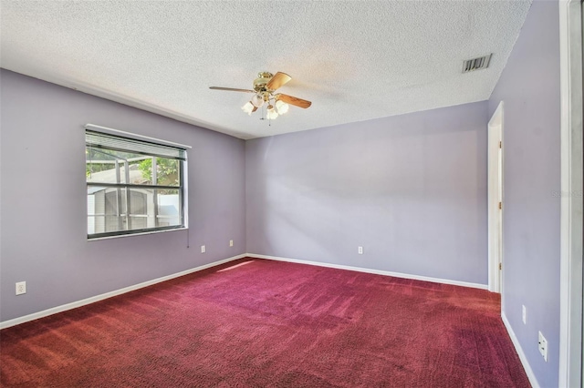 carpeted spare room with ceiling fan, a textured ceiling, and visible vents