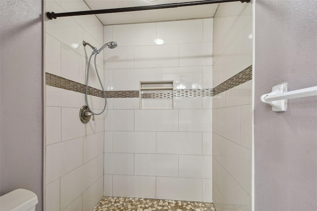 bathroom with toilet and tiled shower
