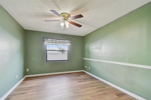 empty room featuring ceiling fan, a textured ceiling, baseboards, and wood finished floors