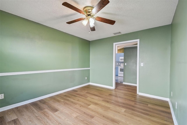 unfurnished bedroom with a textured ceiling, baseboards, wood finished floors, and visible vents