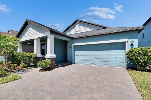 ranch-style home featuring decorative driveway, a garage, and stucco siding
