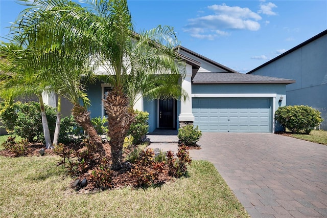 view of front facade featuring stucco siding, decorative driveway, and an attached garage