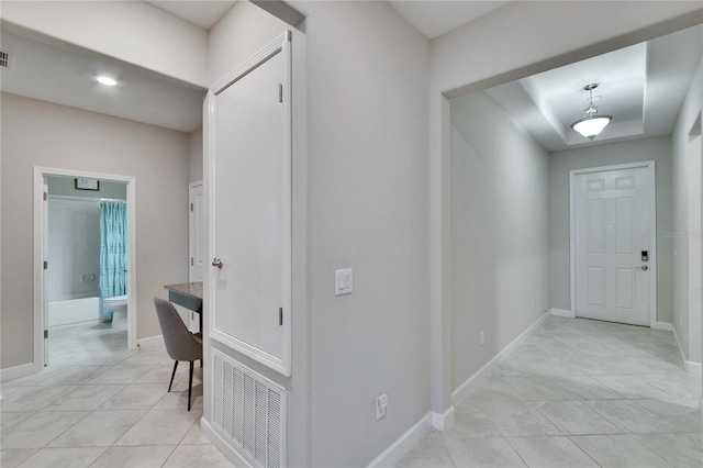 corridor with light tile patterned flooring, visible vents, and baseboards