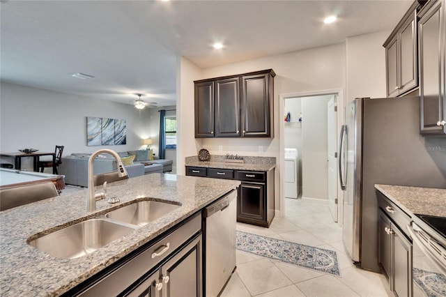 kitchen with light stone counters, washer / clothes dryer, a sink, stainless steel appliances, and open floor plan
