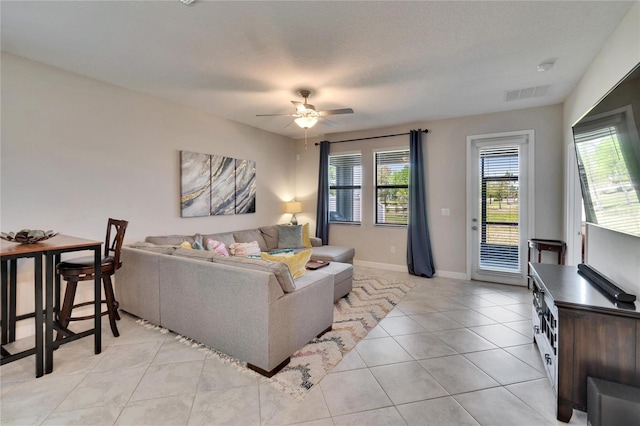 living room with light tile patterned floors, visible vents, a ceiling fan, and baseboards