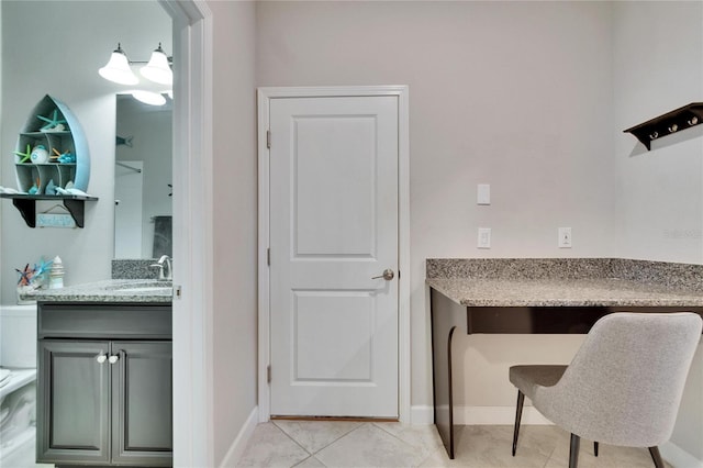 home office with light tile patterned floors, baseboards, and a sink