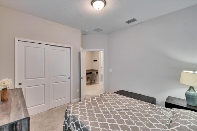 bedroom featuring a textured ceiling, visible vents, carpet flooring, and a closet
