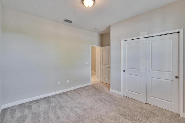 unfurnished bedroom featuring baseboards, visible vents, light carpet, and a closet