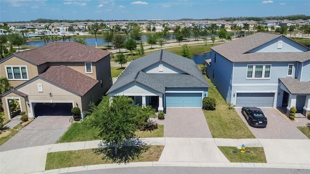 view of front facade with a residential view, driveway, a water view, and stucco siding