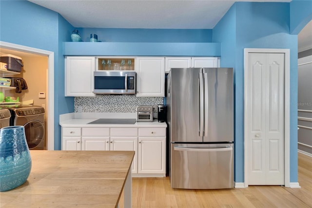 2510 Cross More St, Valrico, FL 33594 - kitchen with independent washer and dryer, white cabinets, appliances with stainless steel finishes, and light wood finished floors