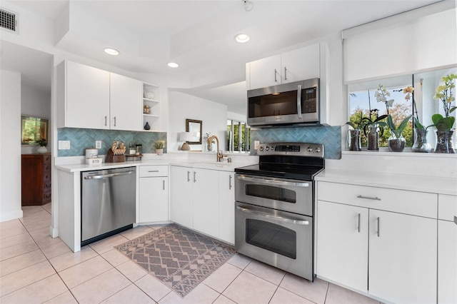 4750 Dolphin Cay Ln S Unit 209, Saint Petersburg, FL 33711 - kitchen featuring appliances with stainless steel finishes, light countertops, open shelves, tasteful backsplash, and white cabinetry