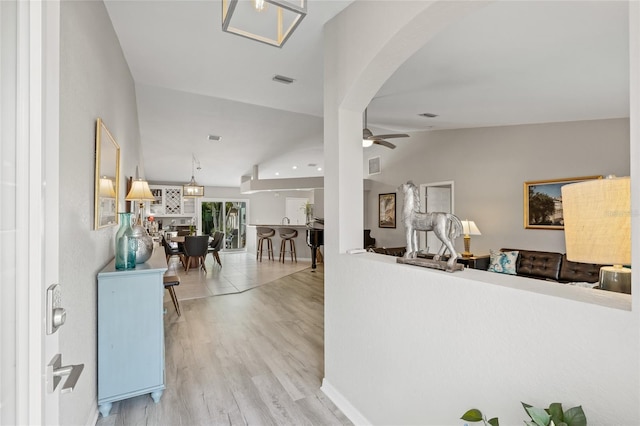 entrance foyer with ceiling fan, visible vents, vaulted ceiling, arched walkways, and wood finished floors