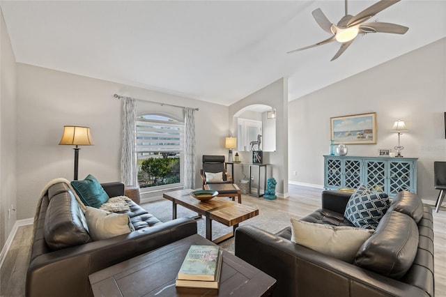 living area with wood finished floors, arched walkways, baseboards, a ceiling fan, and lofted ceiling