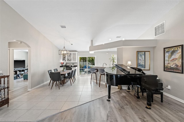 living area featuring arched walkways, visible vents, lofted ceiling, and baseboards