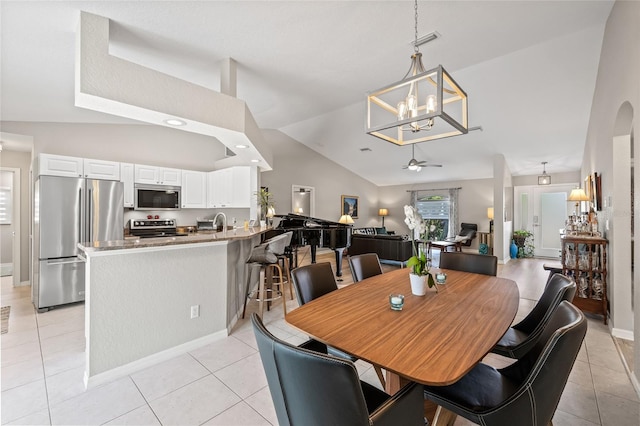 dining room with light tile patterned flooring, baseboards, high vaulted ceiling, and ceiling fan with notable chandelier