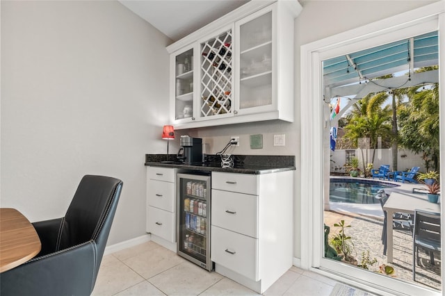 bar featuring bar area, baseboards, light tile patterned floors, and wine cooler