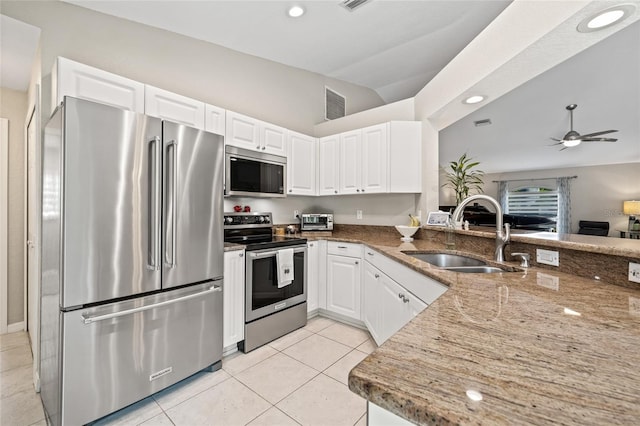 kitchen featuring light stone countertops, stainless steel appliances, lofted ceiling, and a sink