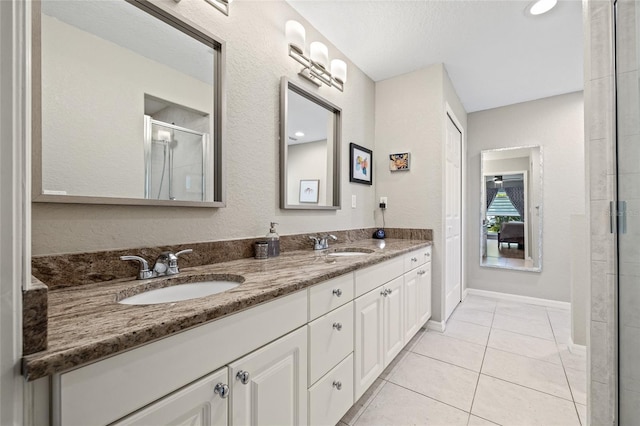 full bath with double vanity, a shower with shower door, tile patterned flooring, and a sink