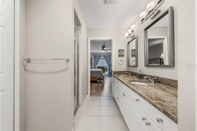 ensuite bathroom featuring tile patterned floors, double vanity, a sink, and connected bathroom