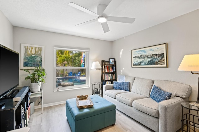 living area with wood finished floors, a ceiling fan, and baseboards