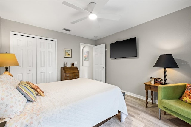 bedroom with light wood-style floors, a closet, ceiling fan, visible vents, and baseboards