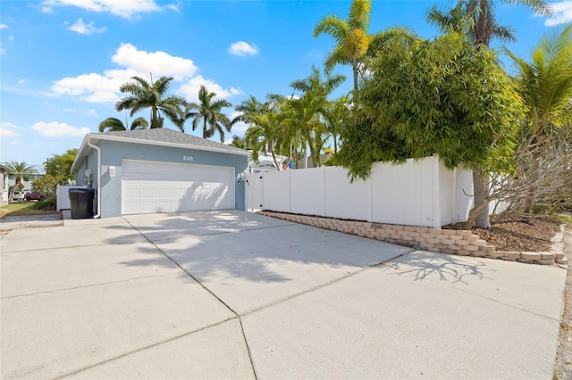 view of side of property with driveway, fence, stucco siding, and a garage
