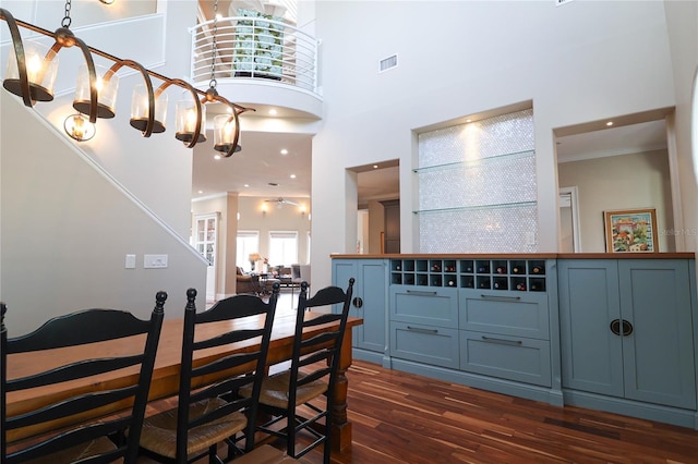 11105 5th St E, Treasure Island, FL 33706 - dining room featuring crown molding, a towering ceiling, visible vents, and dark wood finished floors