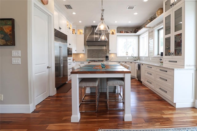 11105 5th St E, Treasure Island, FL 33706 - kitchen with a sink, tasteful backsplash, visible vents, appliances with stainless steel finishes, and premium range hood