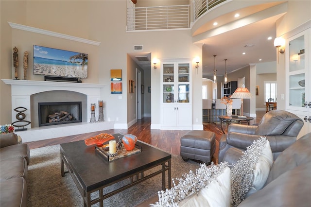 11105 5th St E, Treasure Island, FL 33706 - living area with a fireplace with raised hearth, a high ceiling, wood finished floors, visible vents, and baseboards