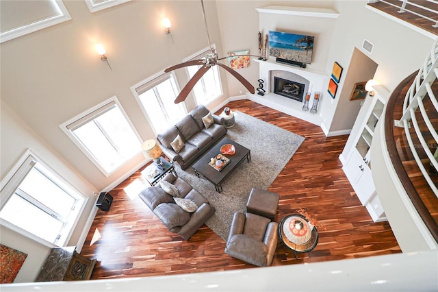 11105 5th St E, Treasure Island, FL 33706 - living area with baseboards, a fireplace with raised hearth, a ceiling fan, wood finished floors, and a high ceiling