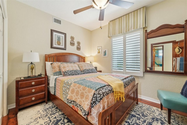 bedroom featuring baseboards, visible vents, wood finished floors, and ceiling fan
