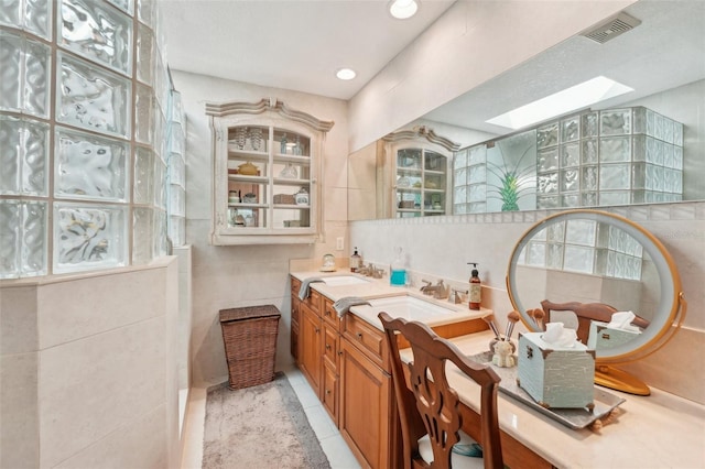 full bathroom with tile walls, visible vents, a skylight, and a sink