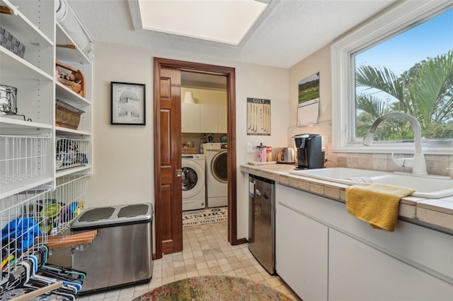 laundry area with washing machine and dryer, cabinet space, a sink, and a textured ceiling