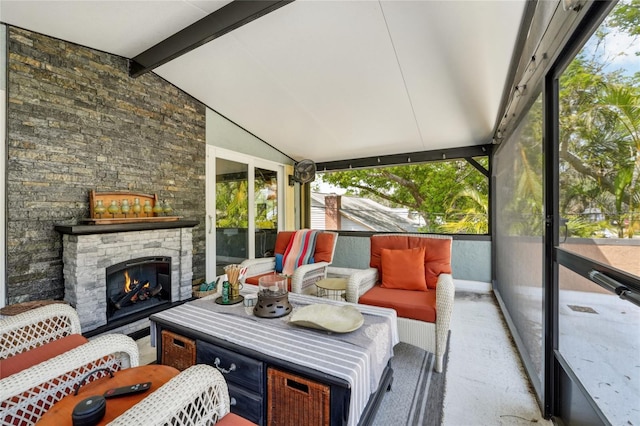 sunroom / solarium with an outdoor living space with a fireplace and beamed ceiling