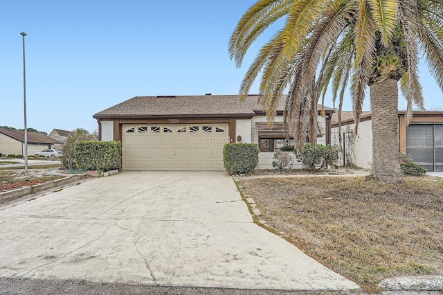view of front of home with stucco siding, driveway, a garage, and a shingled roof