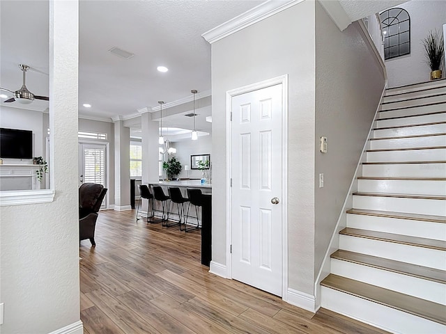 stairs with baseboards, wood finished floors, and crown molding