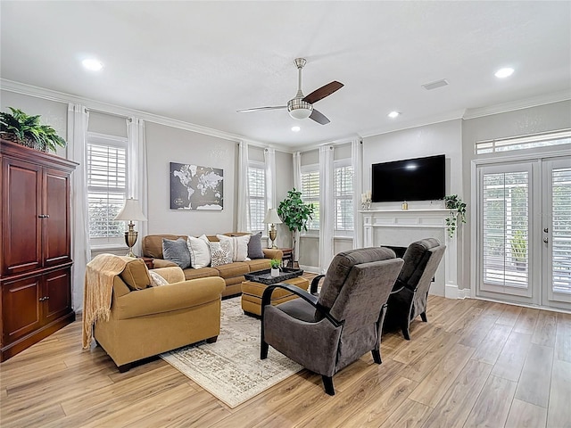 living area with ornamental molding, a ceiling fan, light wood-style floors, and plenty of natural light