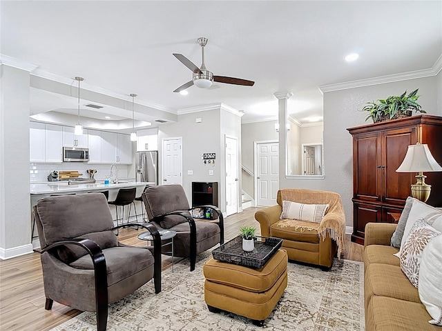 living room featuring ornamental molding, light wood finished floors, and a ceiling fan