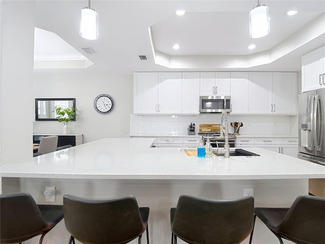 kitchen with backsplash, stainless steel appliances, and white cabinetry