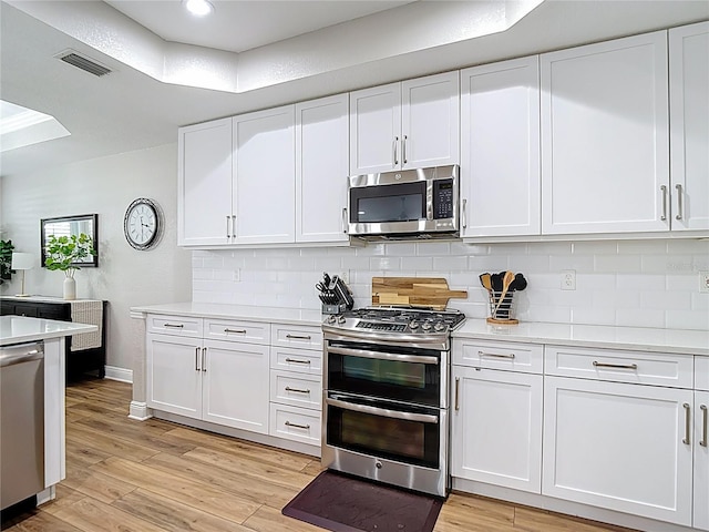 kitchen featuring appliances with stainless steel finishes, visible vents, decorative backsplash, and light countertops